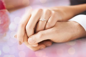 Ehepaar reicht sich die Hände, Frau trägt Diamantring